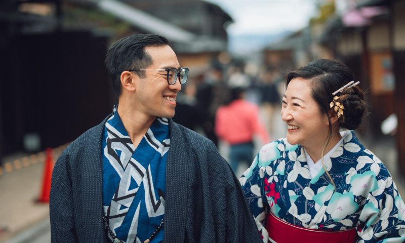 Couple dressed in kimono laughing as they walk through a traditional street in Kyoto
