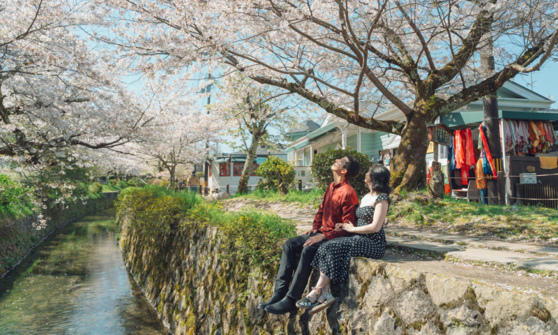 Couple sitting by the canal of the Philosopher's Path of Kyoto.