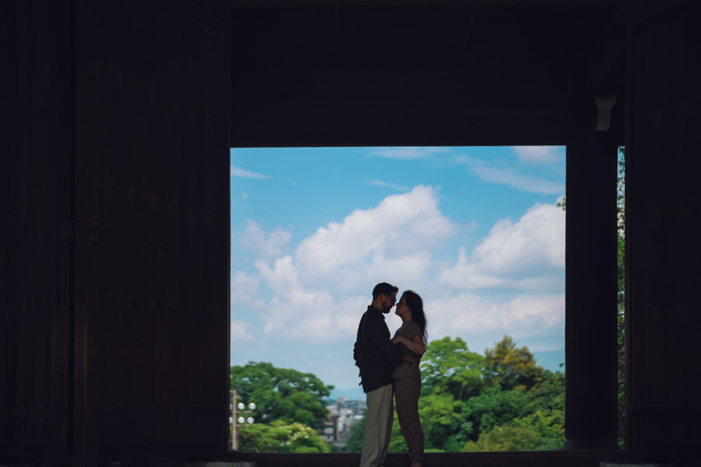 Couple's silhouettes against the sky framed by the wooden doors of the Chion-in Temple in Kyoto, Japan